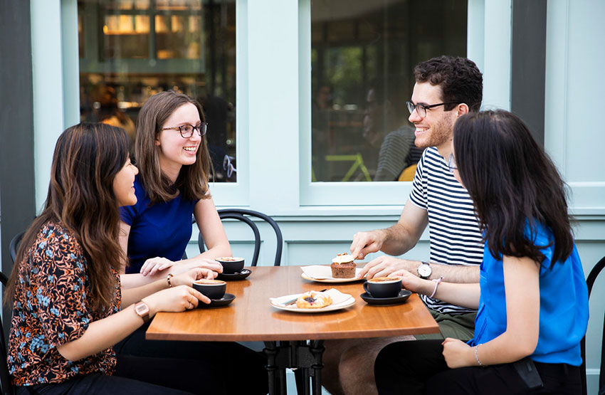 Four students sitting and talking in a cafe